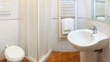 Un baño con inodoro, cabina de ducha y lavamanos.