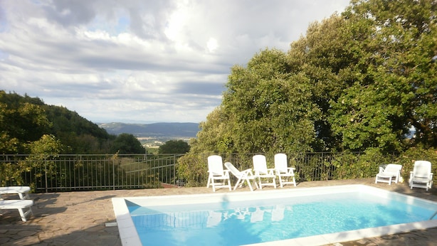 Una piscina con sillas de descanso blancas y un patio de piedra.
