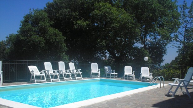 Ein Pool mit weißen Liegestühlen und einer Steinterrasse.