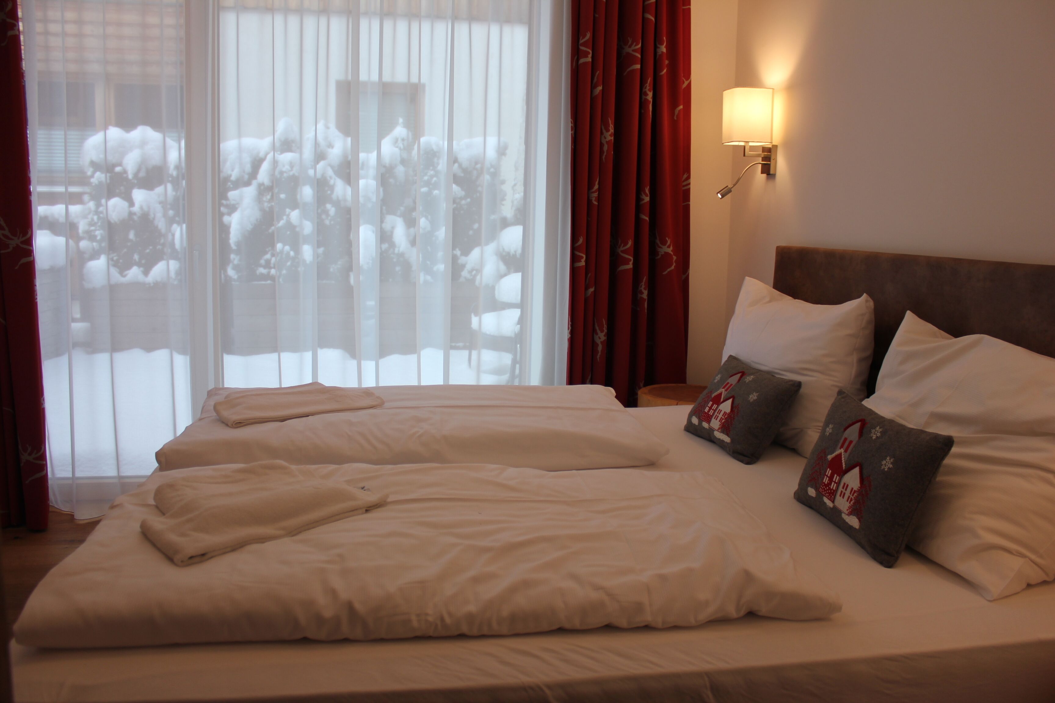 A hotel room with a large bed, two bedside tables, and a window with curtains.