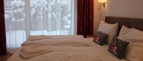 A hotel room with a large bed, two bedside tables, and a window with curtains.