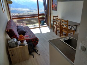 Un salon confortable avec un canapé, un petit bureau équipé d’un ordinateur et une vue sur un balcon.