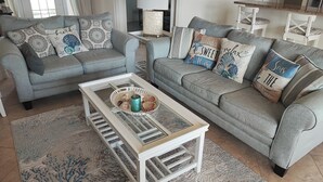 Un soggiorno con due divani grigi, un tavolino da caffè bianco e cuscini decorativi.