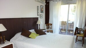 Een hotelkamer met een groot bed, een nachtkastje, een stoel en uitzicht op de omgeving door een schuifdeur van glas.