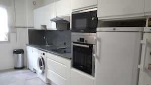 Een moderne keuken met witte kastjes, een Bosch oven, een magnetron en een vaatwasser.