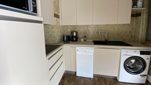 A compact kitchen with a dishwasher, washing machine, and a coffee maker. - Top-floor apartment with amazing sea view (Menton)
