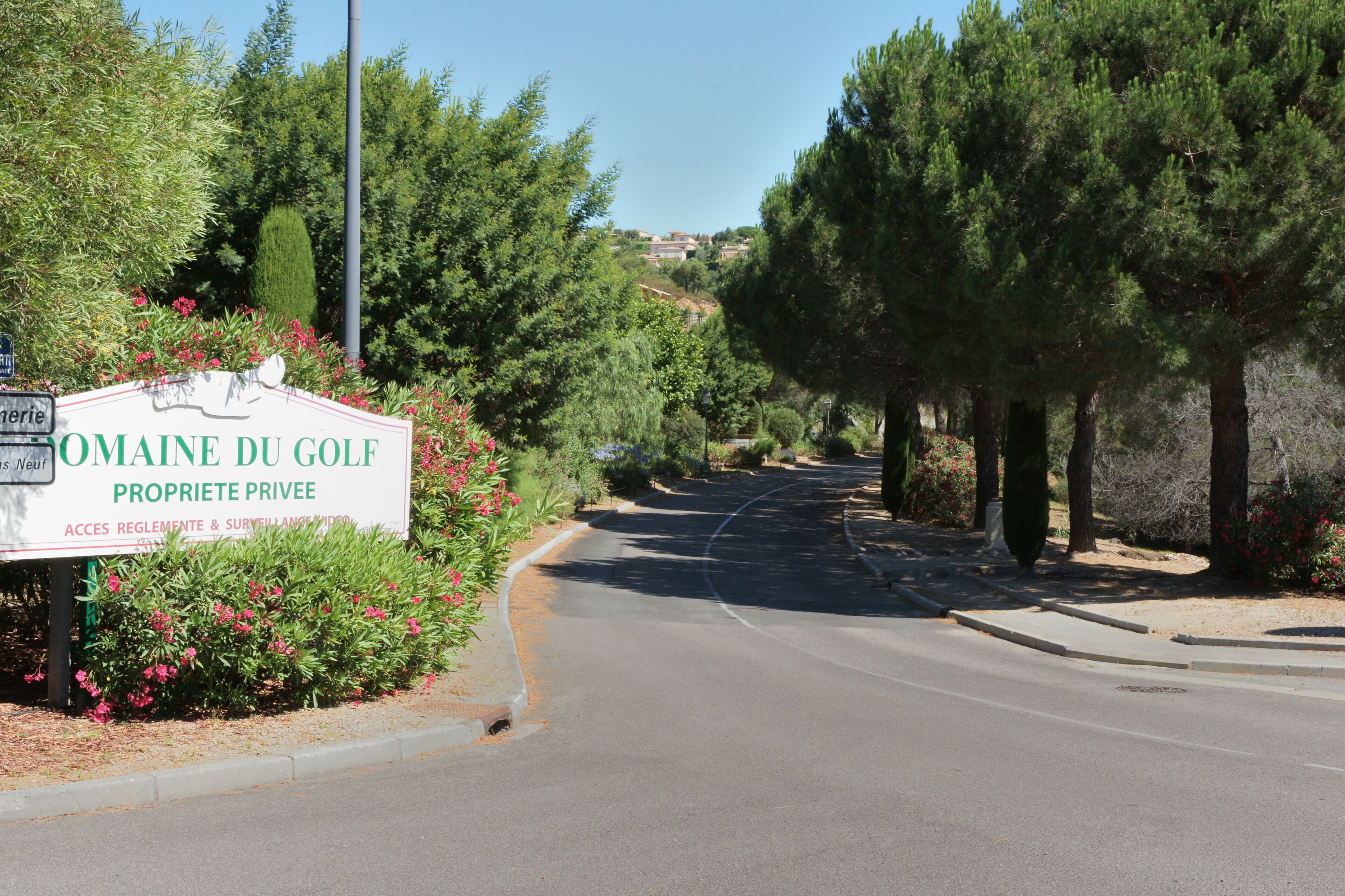 A sign for "Omaine du Golf" with a private property notice, surrounded by greenery and trees.