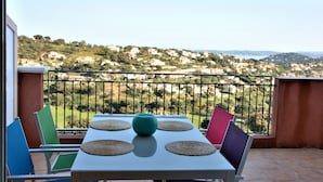 Een balkon met een tafel en stoelen, met uitzicht op een heuvel met huizen.