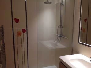 Ein Badezimmer mit einer Duschkabine, einem Waschbecken und einem Spiegel.