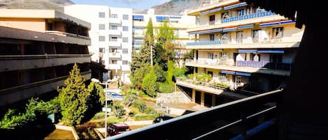 A multi-story hotel with balconies, a parking area, and a view of a mountain.