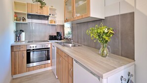 Une cuisine moderne avec des meubles en bois, des appareils électroménagers en acier inoxydable et un vase rempli de fleurs posé sur le plan de travail.
