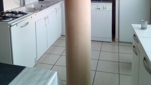 Una cocina con gabinetes blancos, estufa, microondas y pileta.