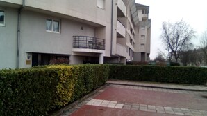 Un edificio residencial de varios pisos con balcones, un patio empedrado y una siega bien cuidada.