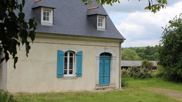 A house with a sloped roof, a small porch, and a grassy yard.