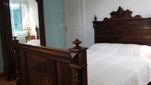 A bedroom with a wooden bed, a mirror, and a white door.