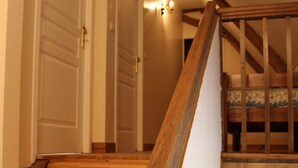 A wooden staircase with a handrail leading to a bedroom with a bed.