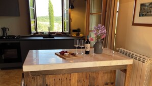 A kitchen with a marble countertop, wooden stools, a wine bottle, and a vase of flowers. - Fantastic apartment with terrace and pool overlooking Volterra (Volterra (PI))
