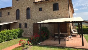 A stone building with a patio area featuring outdoor furniture and a pergola. - Fantastic apartment with terrace and pool overlooking Volterra (Volterra (PI))