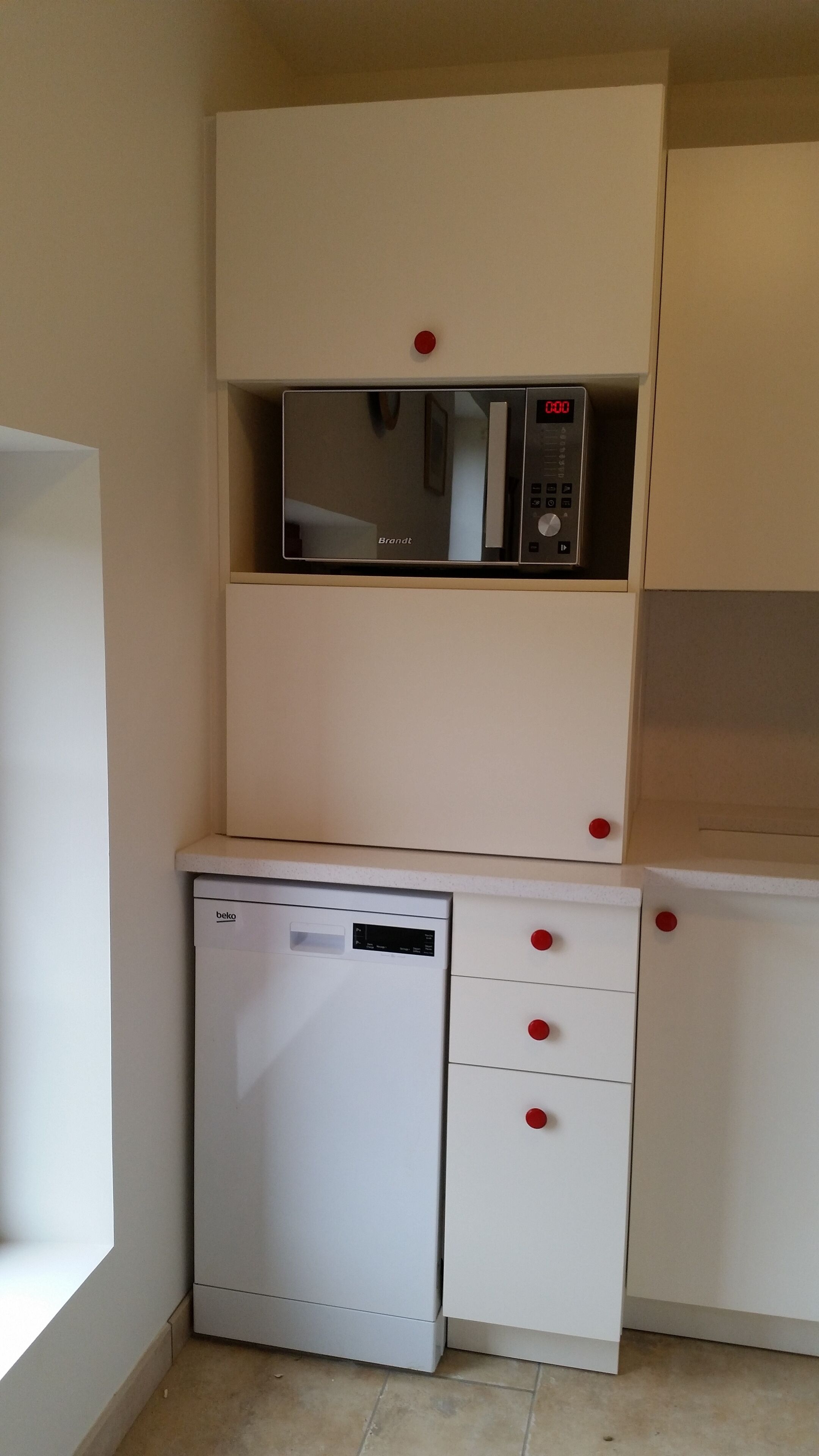 A compact kitchen with a built-in microwave and a small dishwasher.