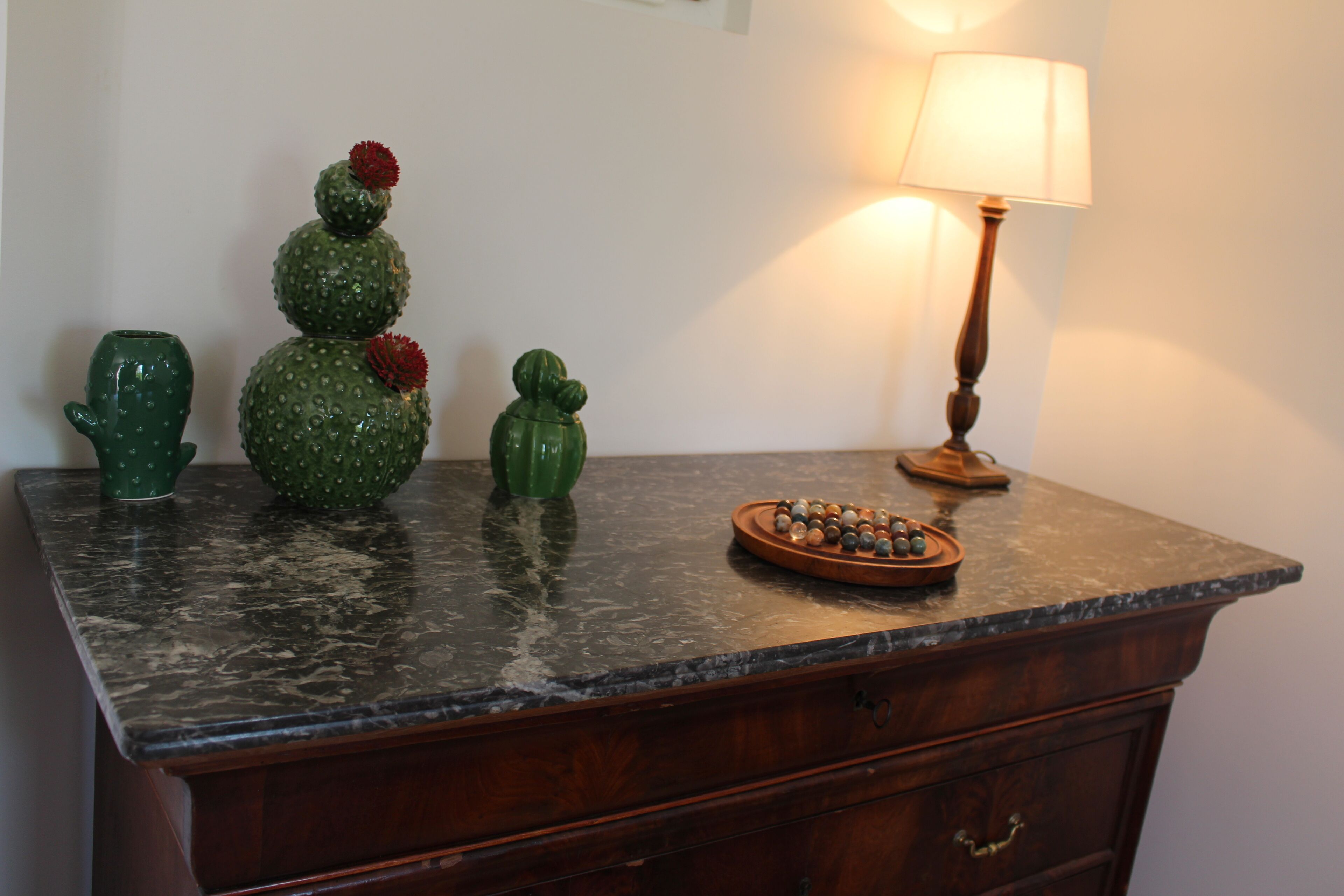 Una encimera de cocina con esculturas decorativas de cactus, una lámpara y una bandeja de cuentas.