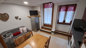 A compact living space with a sofa, a dining table, a TV, a refrigerator, and a washing machine. - Self-contained apartment in house in Cauterets  (Hautes-Pyrénées)