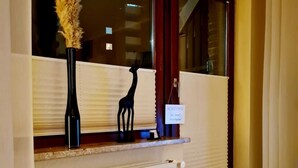 A reception area with a window, a radiator, a black mat, and a decorative vase with pampas grass. - Modern apartment in the heart of Schleswig (Schleswig)