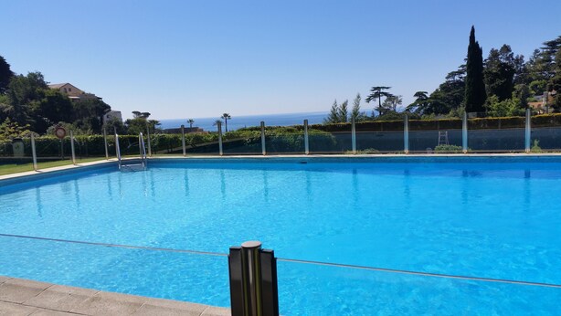 Une piscine d’un bleu éclatant, avec vue sur l’océan et la végétation environnante.