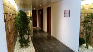 Un couloir doté d’un sol carrelé, d’un mur en bois d’un côté et d’une enseigne fixée au mur.