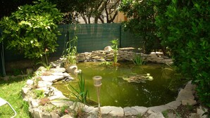 A small pond with a stone border, surrounded by rocks and plants.