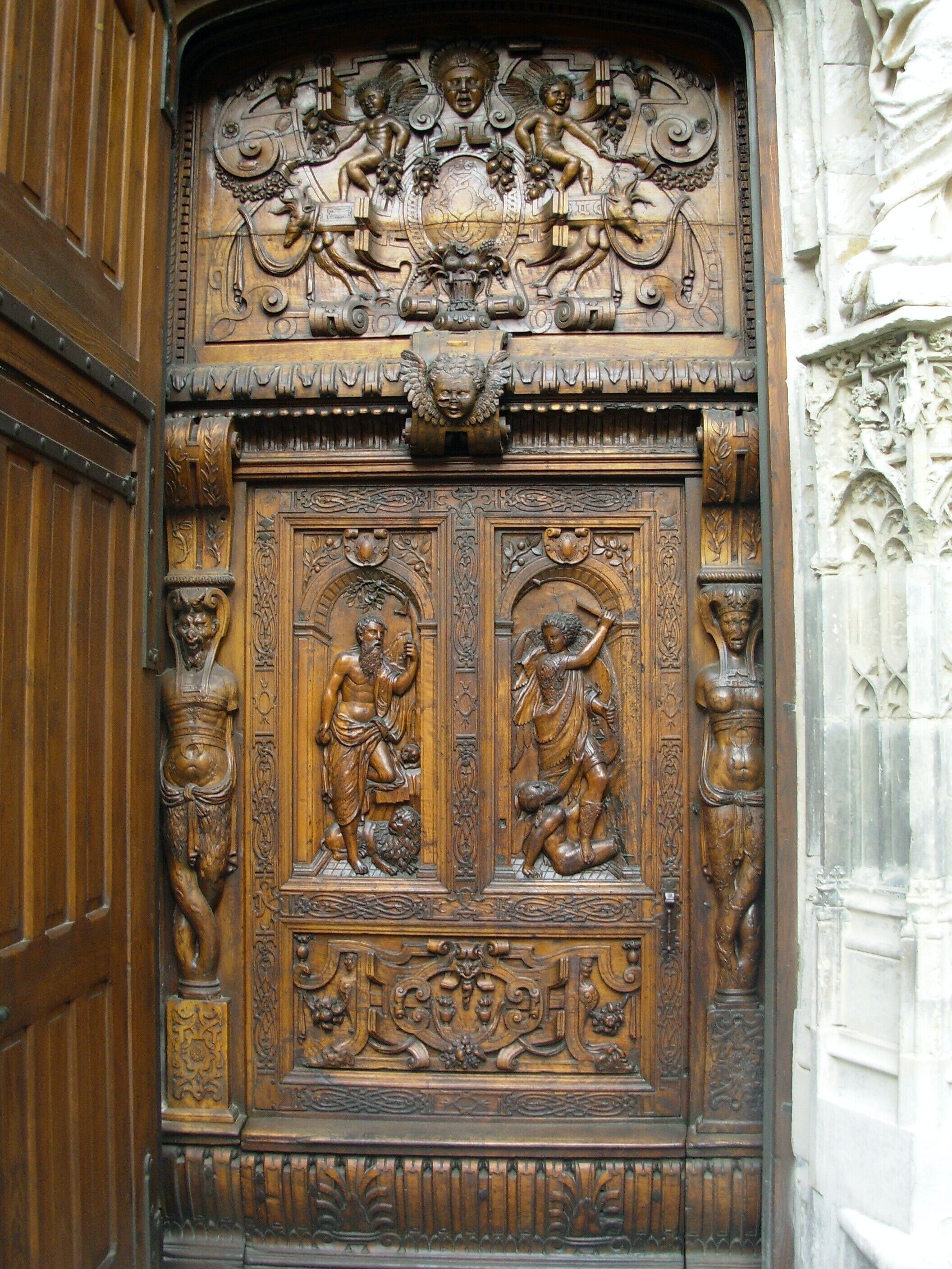 A wooden door with intricate carvings, including figures and decorative patterns.