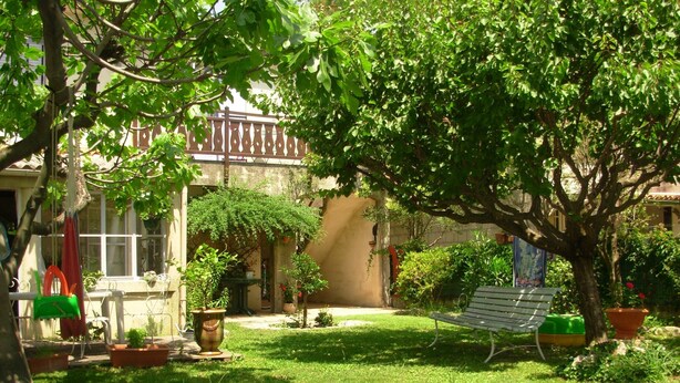 A courtyard with a hammock, potted plants, a blue inflatable pool, and a building with a balcony.