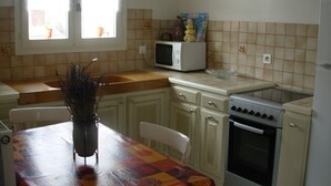 A kitchen with a window, a microwave, an oven, and a dining table with chairs.