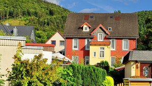 A row of colorful houses with a forested hill in the background.