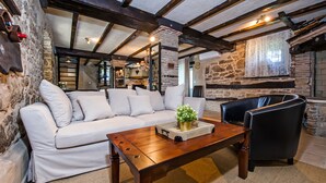 A cozy living area with a white sofa, a wooden coffee table with a plant, and a black leather chair. - Stylish Istrian Retreat with Pool, Tennis Court & Outdoor Kitchen (Pican)