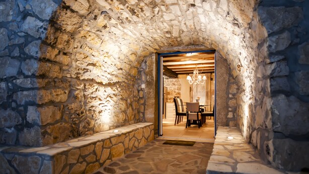 A stone-walled corridor leading to a dining area with a chandelier. - Stylish Istrian Retreat with Pool, Tennis Court & Outdoor Kitchen (Pican)