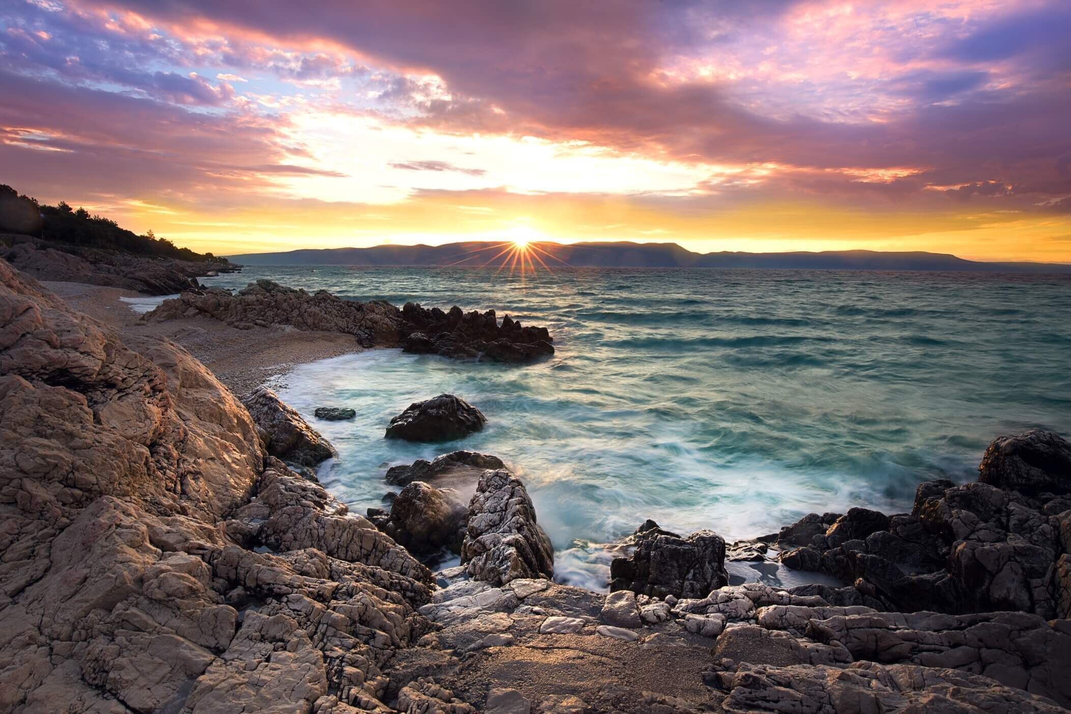 Eine felsige Küste mit Sonnenuntergang über dem Meer.