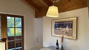 A dining area with a table, chairs, a wine bottle, and a framed picture on the wall.