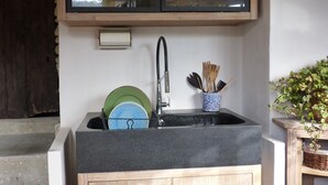 Eine kompakte Küche mit eingebautem Spülbecken, Holzschränken und einem Schrank mit Glastür über dem Spülbecken.