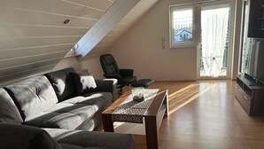 Un salon moderne avec un canapé, une table basse et un téléviseur.