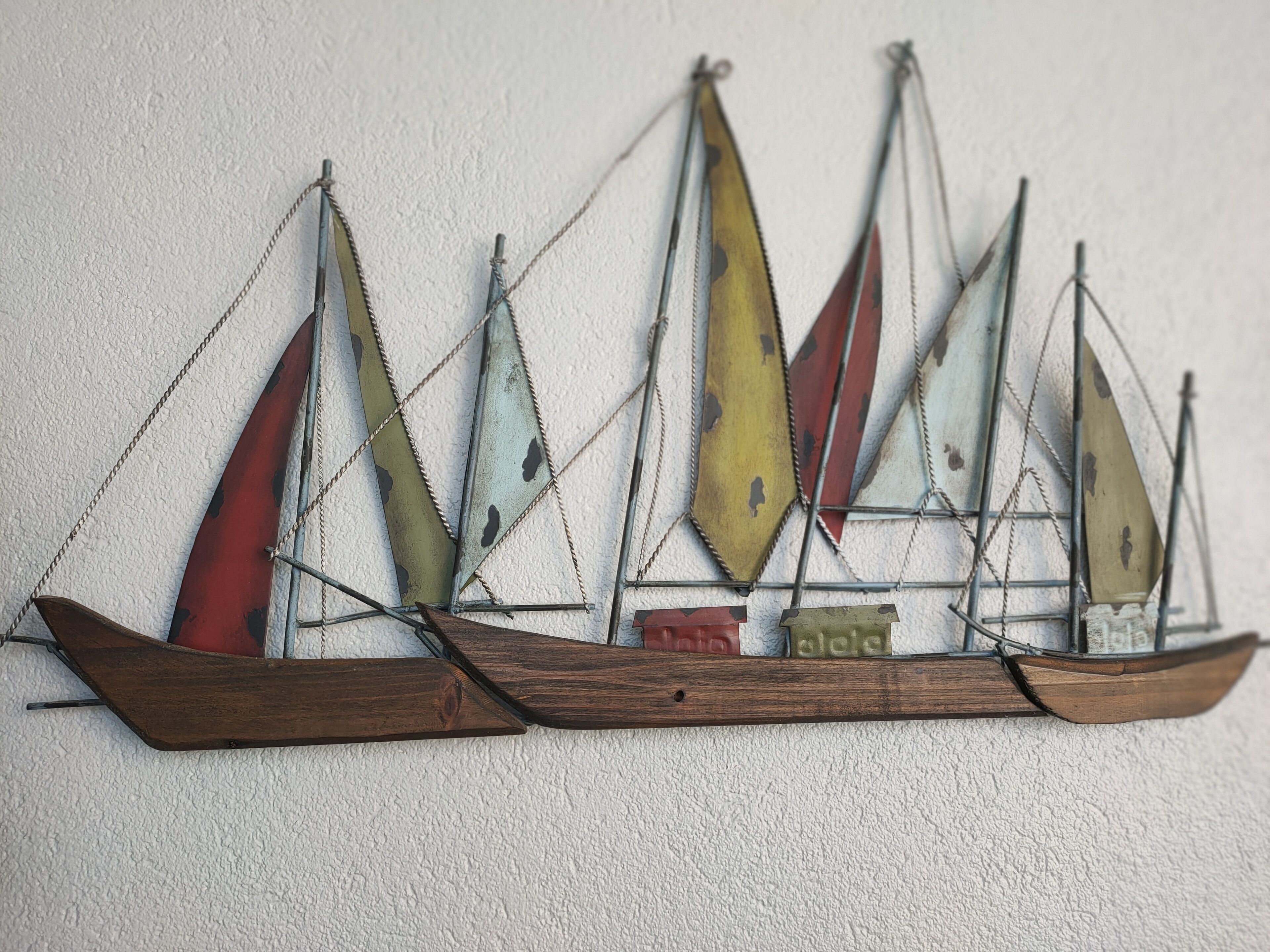 Un modèle de voilier décoratif à accrocher au mur, doté de plusieurs voiles.