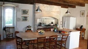 Una cocina rústica con una isla grande, sillas de madera y luces colgantes.