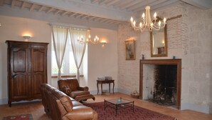 Una sala de estar con sofás de cuero, un aparador de madera, una chimenea y una araña.