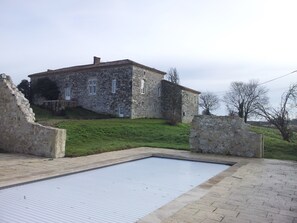 A stone building with a rectangular swimming pool in front.