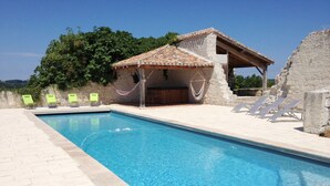 Una piscina con sillas de descanso y una zona de estar cubierta.