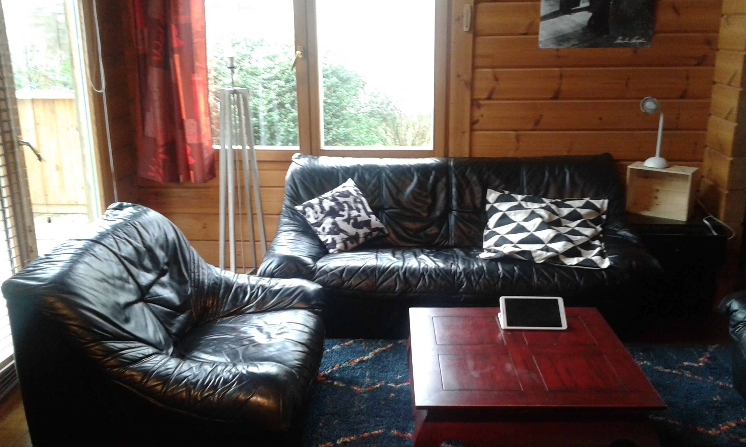 Ein Wohnzimmer mit einer schwarzen Ledersofa, einem passenden Sessel und einem Holztisch.