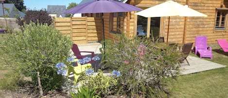 A wooden cabin with a patio area featuring outdoor furniture and umbrellas.