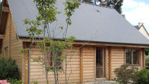 Une cabane en bois avec un toit en pente, une porte d’entrée et un petit porche.