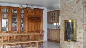 Een eethoek met een houten tafel en stoelen, een kroonluchter en houten kasten met glazen deuren.