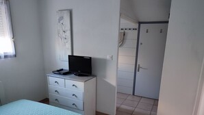 A bedroom with a bed, a dresser, a television, and a door leading to another room. - semi-detached villa sleeps 6, 3-star furnished holiday accommodation (Saint-Cyprien plage)