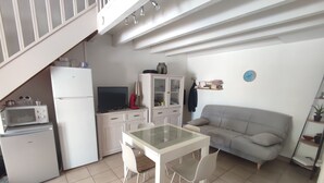 A compact kitchen with a dining table and chairs, a sofa, and a staircase leading to an upper level. - semi-detached villa sleeps 6, 3-star furnished holiday accommodation (Saint-Cyprien plage)